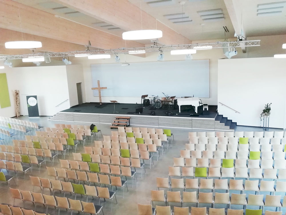 Innenaufnahme Gottesdienstraum FeG Wetzlar. Stuhlreien führen zur Bühne, die leicht erhaben ist.